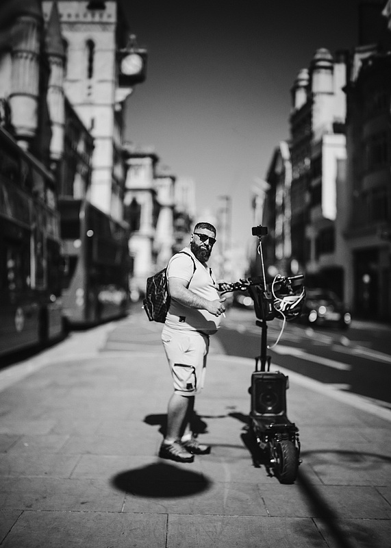 Man standing next to his electric scooter in London